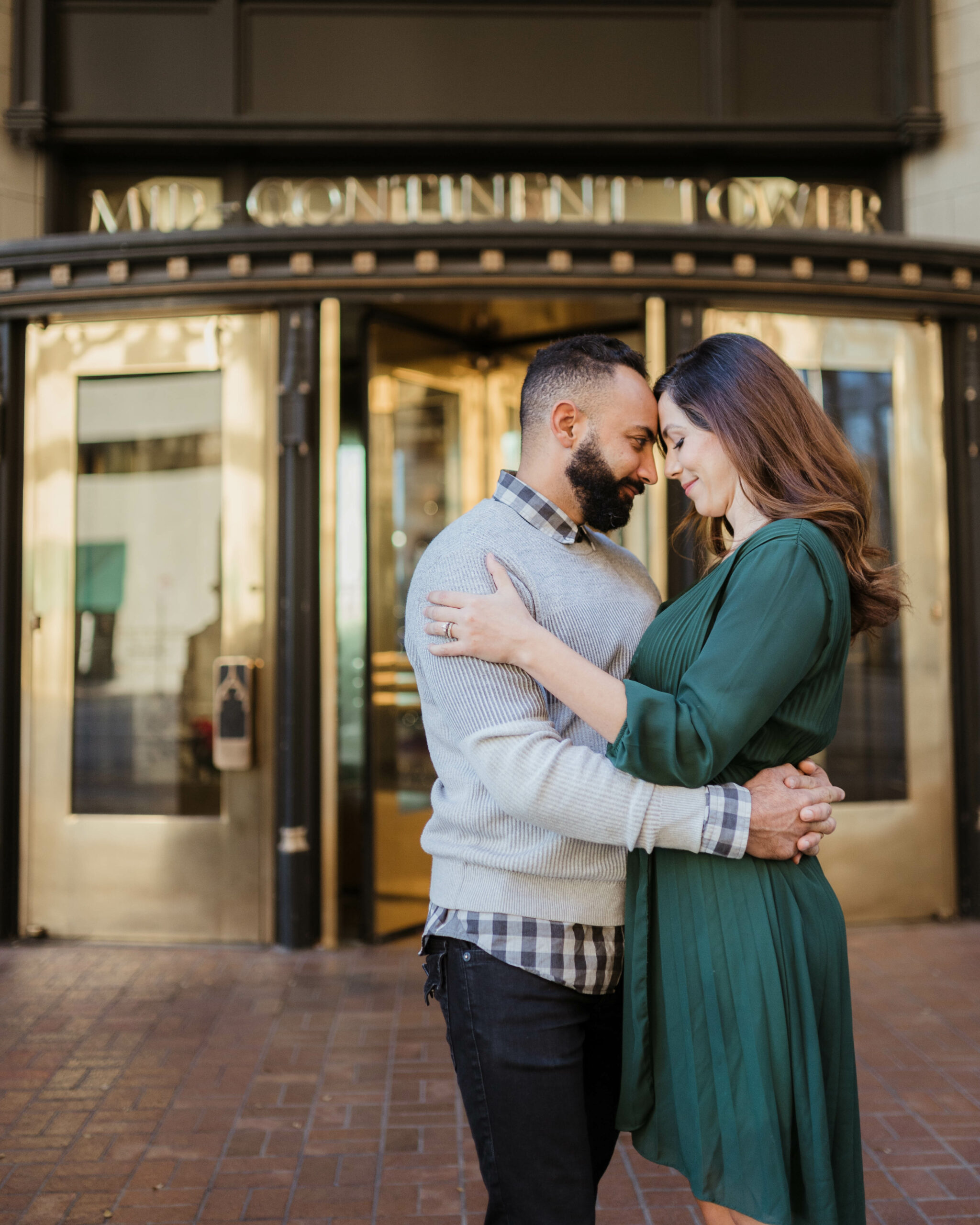Couple Holding Each Other in Front of Tulsa Downtown Building for Christmas photos